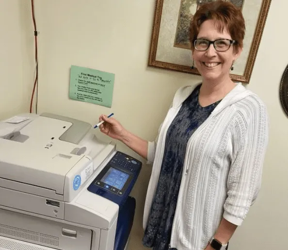 Happy customer standing in front of a printer, showcasing reliable office equipment and professional service plans for business efficiency.